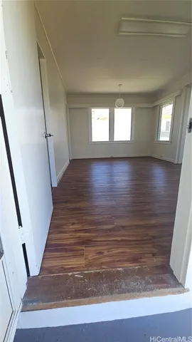a view of an empty room with wooden floor and stairs