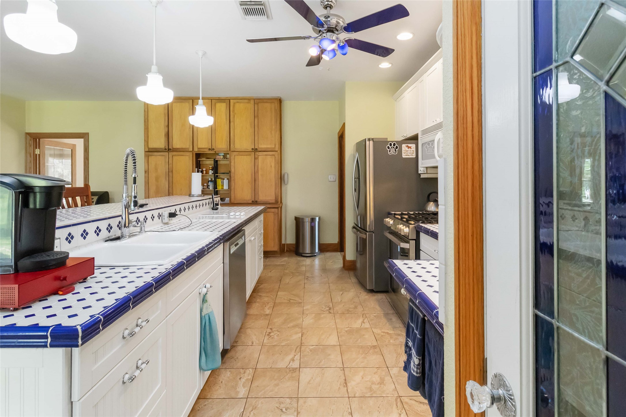 1208 Jeddo Road Rosanky, TX 78953 - Photo 8 of 40 A vibrant kitchen features a blue and white tiled island, stainless steel appliances, and ample cabinetry.