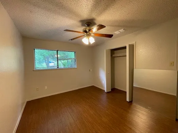 a view of an empty room with window and wooden floor