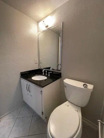 a bathroom with a granite countertop toilet sink and mirror