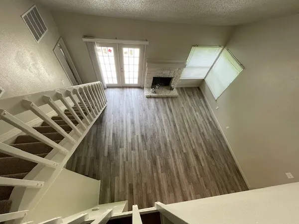 a view of an empty room with wooden floor and stairs