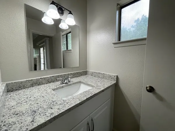 a bathroom with a granite countertop sink a large mirror and a window