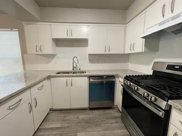 a kitchen with granite countertop a stove sink and cabinets