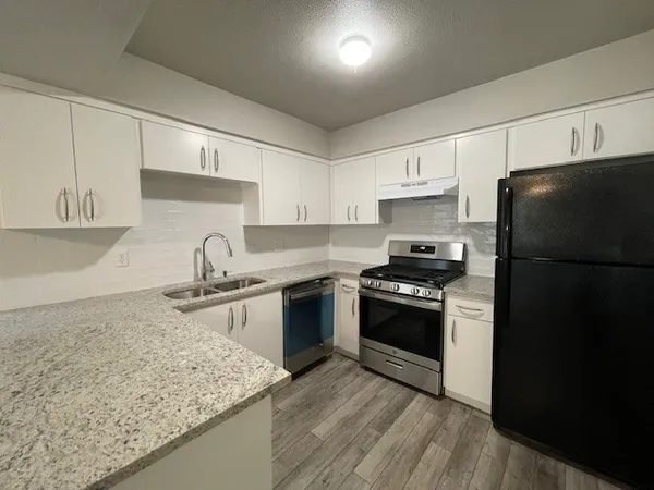 a kitchen with granite countertop a refrigerator stove and sink