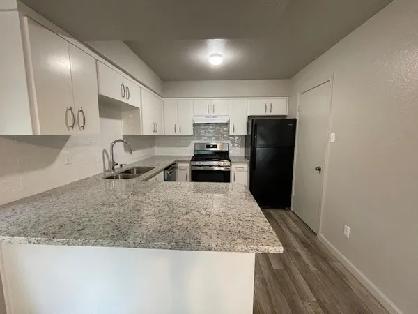 a kitchen with granite countertop a refrigerator stove and sink