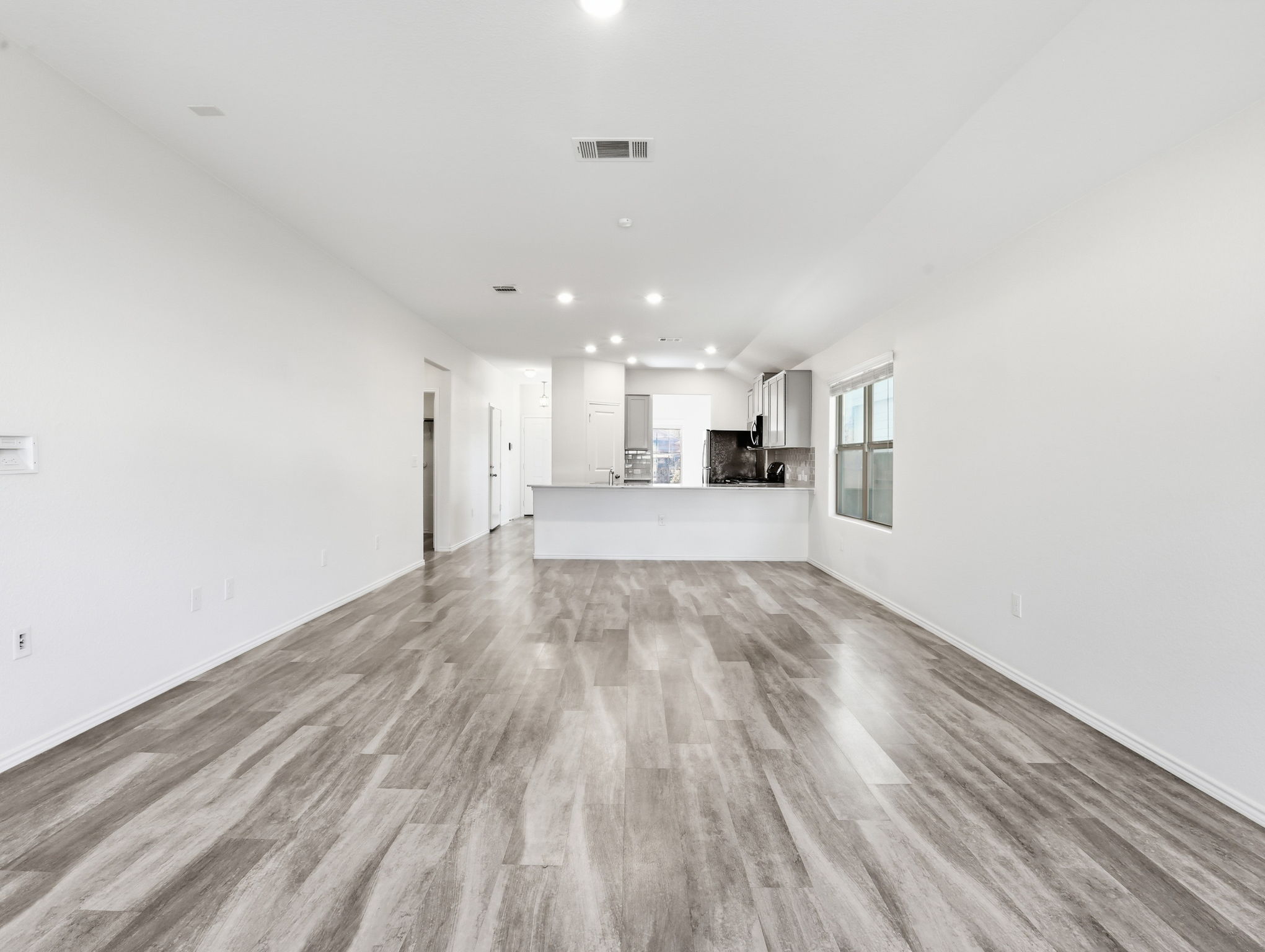 5900 Bell Tower Lane Austin, TX 78747 - Photo 12 of 26 Unfurnished living room featuring light wood-style flooring, recessed lighting, and lofted ceiling