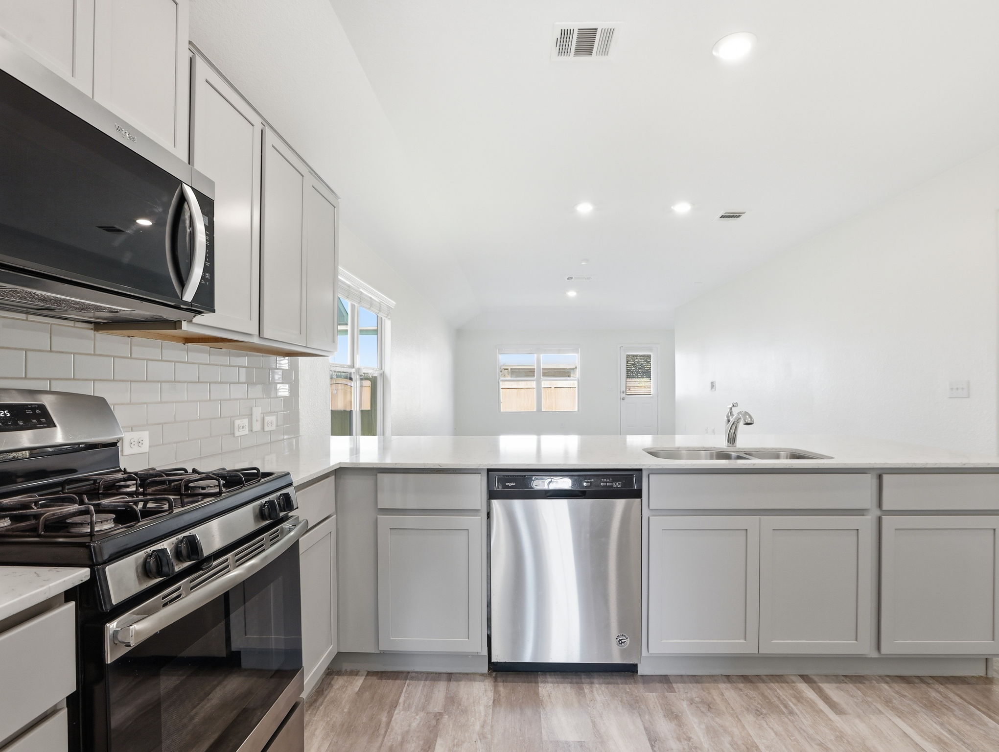 5900 Bell Tower Lane Austin, TX 78747 - Photo 3 of 26 Kitchen with stainless steel appliances, gray cabinets, a peninsula, light wood-style floors, and recessed lighting