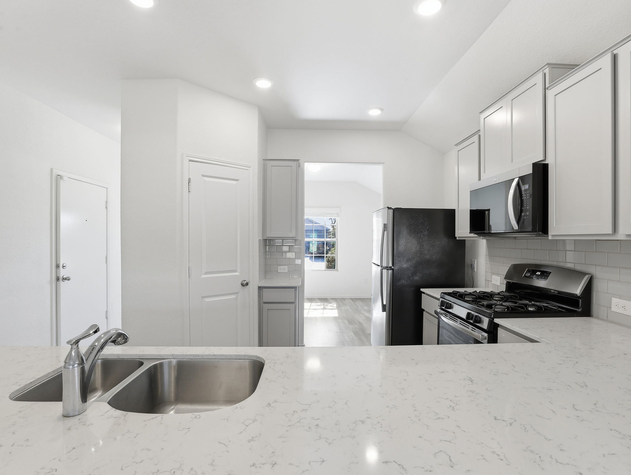 5900 Bell Tower Lane Austin, TX 78747 - Photo 5 of 26 Kitchen featuring stainless steel appliances, light stone countertops, decorative backsplash, vaulted ceiling, and recessed lighting