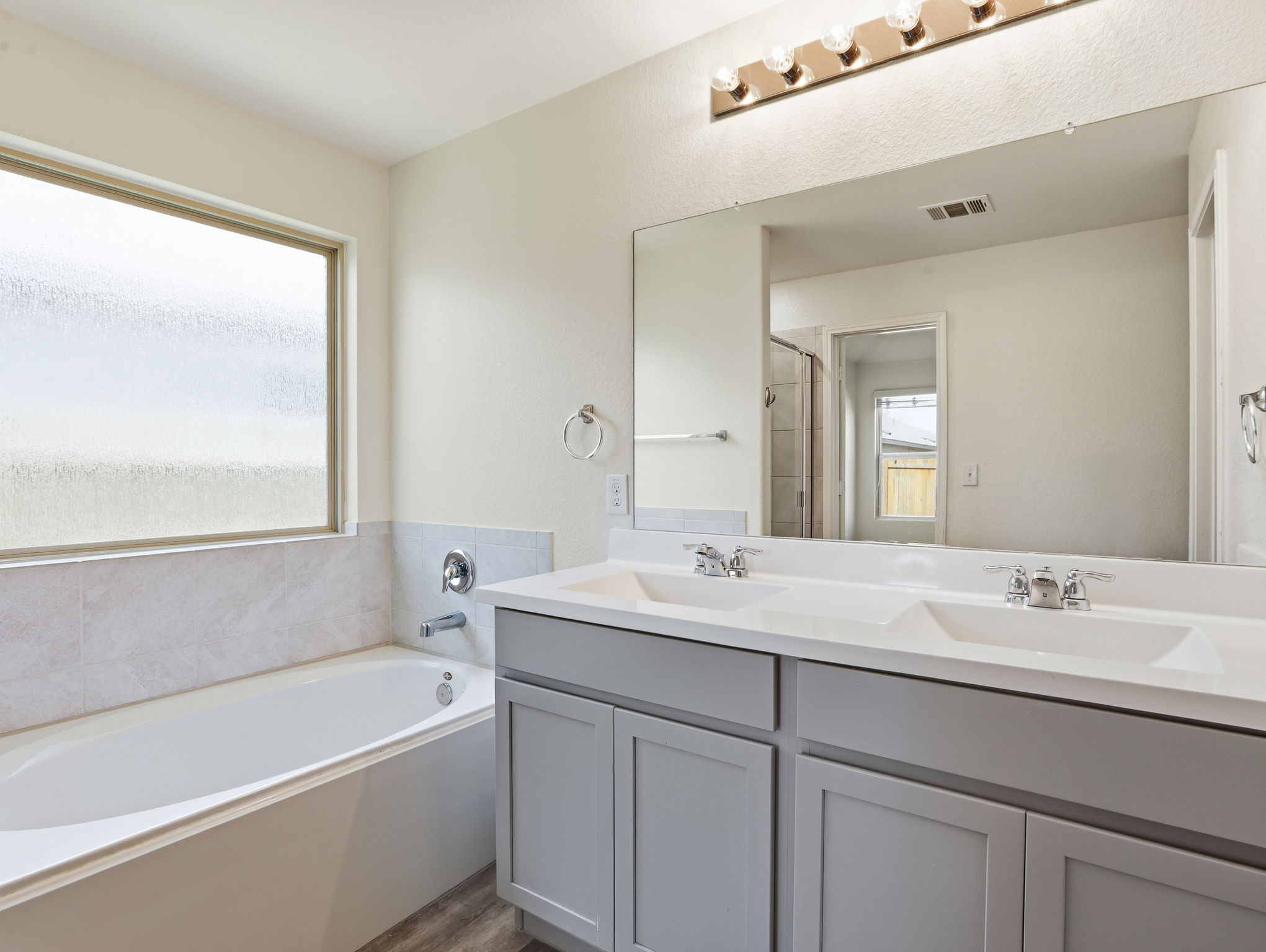 5900 Bell Tower Lane Austin, TX 78747 - Photo 10 of 26 Bathroom with double vanity, a garden tub, light wood-type flooring, and a shower stall