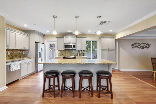 a kitchen with kitchen island granite countertop a stove a sink a center island and cabinets