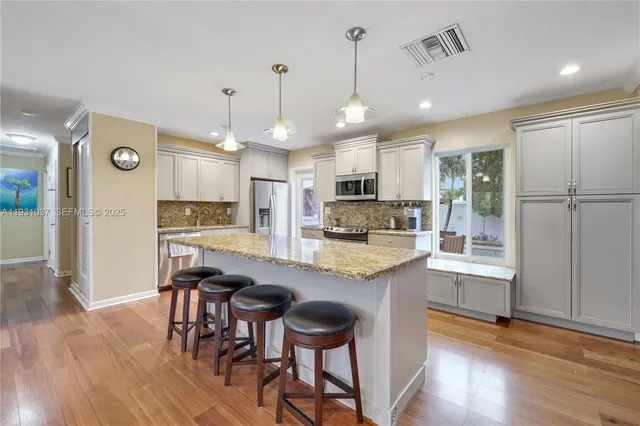 a kitchen with kitchen island granite countertop wooden floors and refrigerator