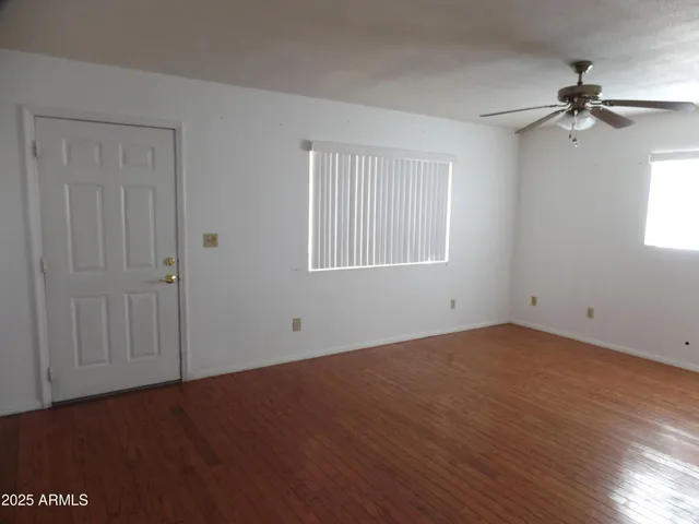 an empty room with wooden floor closet and windows
