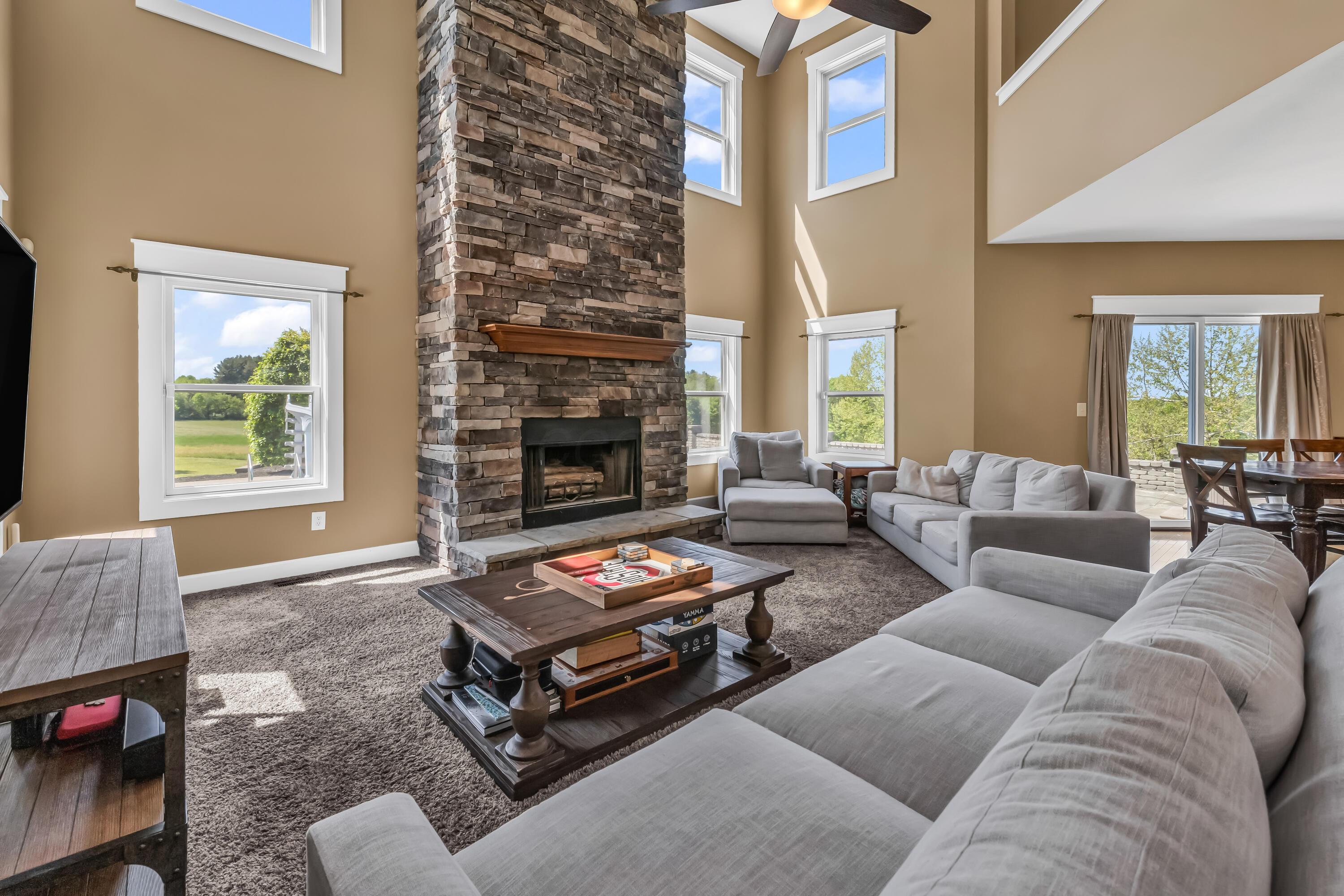 16689 Bailor Road Laurelville, OH 43135 - Photo 26 of 73 • Light sand carpet
• Tan painted walls
• Two story ceiling
• New lighted ceiling
fan ~ 2025
• Stone floor to ceiling,
woodburning fireplace
with raised hearth &
mantle