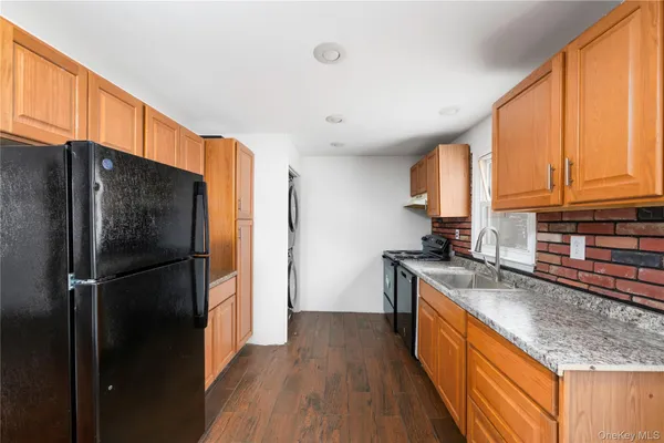 a kitchen with stainless steel appliances granite countertop a refrigerator a sink dishwasher and wooden cabinets with wooden floor