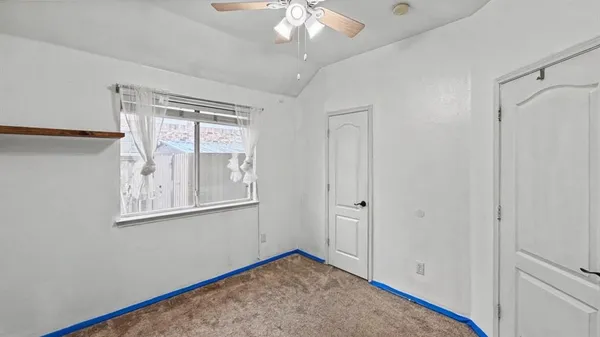 a view of an empty room with window and chandelier fan