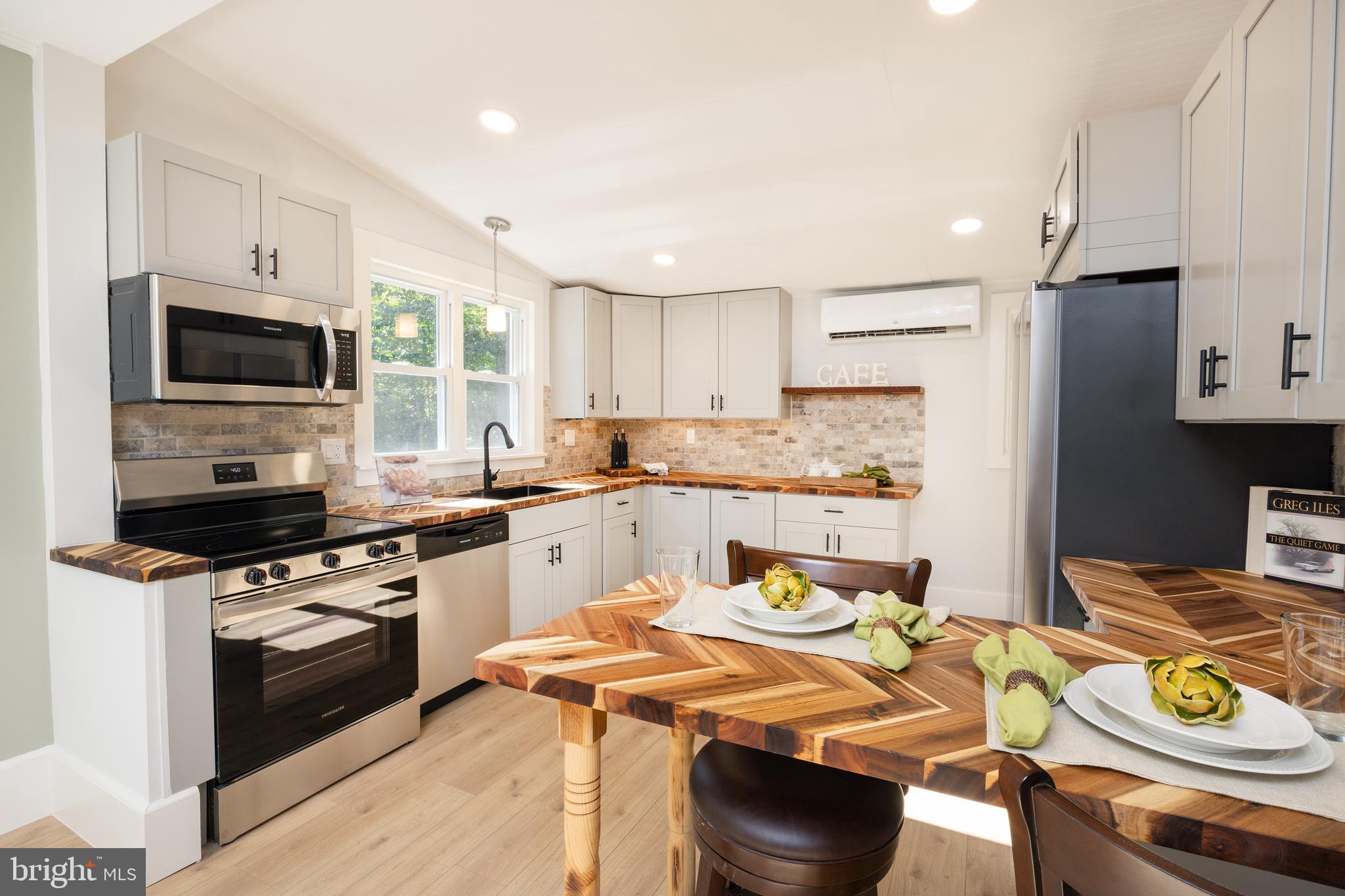 107 Rock Ridge Road Ottsville, PA 18942 - Photo 8 of 24 a kitchen with stainless steel appliances granite countertop a sink a stove a refrigerator cabinets and a dining table with wooden floor