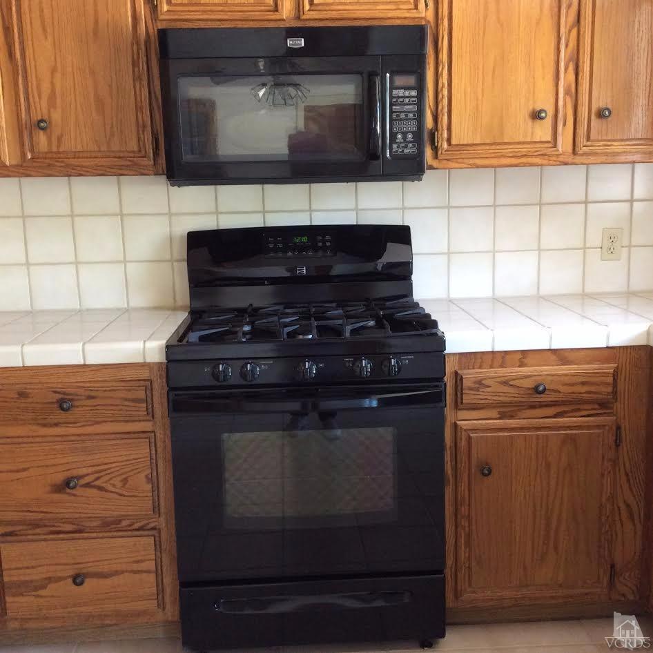 22813 Clover Spring Place Tehachapi, CA 93561 - Photo 10 of 20 a kitchen with wooden cabinets and a stove top oven