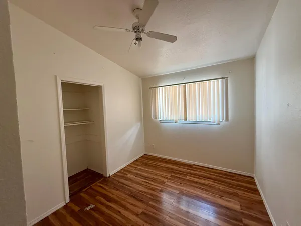 a view of an empty room with wooden floor and a window
