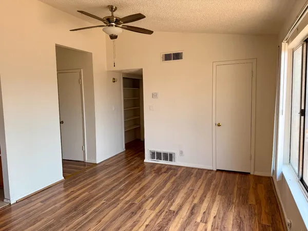 an empty room with wooden floor closet and windows