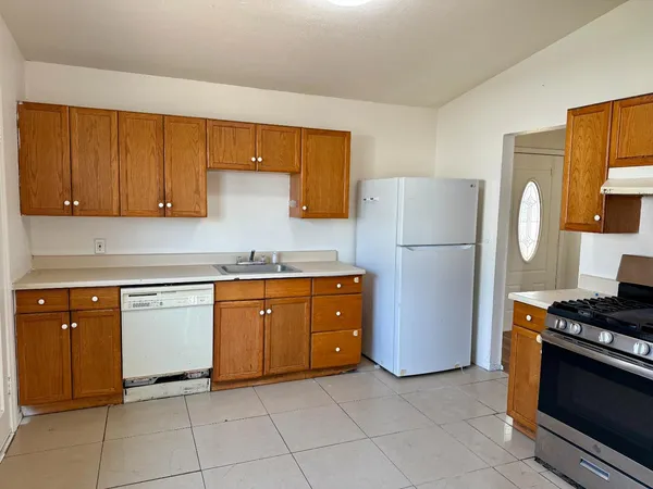 a kitchen with granite countertop a refrigerator and a stove top oven