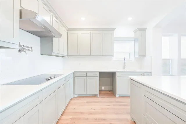 a kitchen with a sink dishwasher a stove and white cabinets with wooden floor
