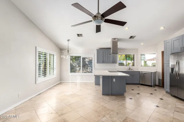a large kitchen with kitchen island a large window and stainless steel appliances