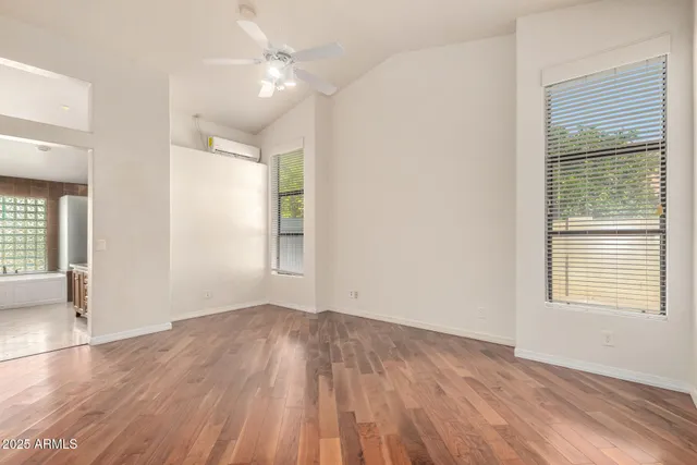an empty room with wooden floor and windows