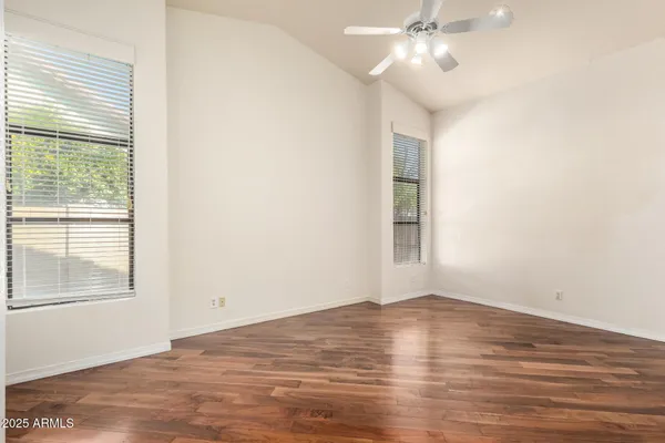 a view of empty room with wooden floor and fan
