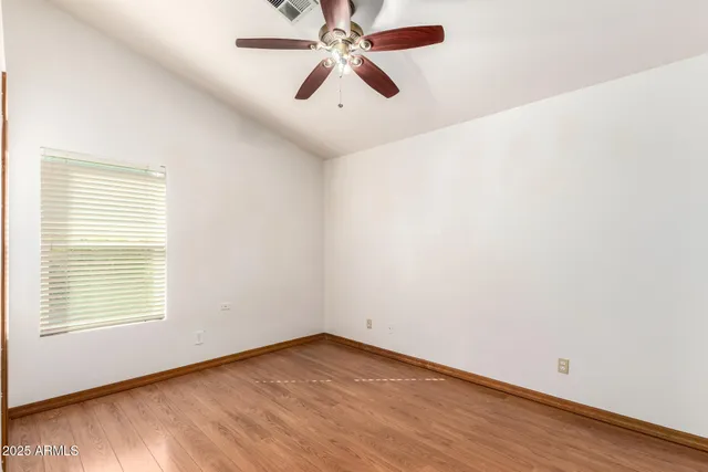 an empty room with wooden floor chandelier fan and windows