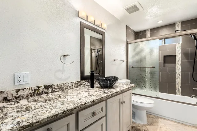 a bathroom with a granite countertop sink toilet and shower