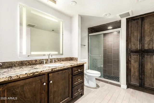 a bathroom with a granite countertop sink toilet and shower