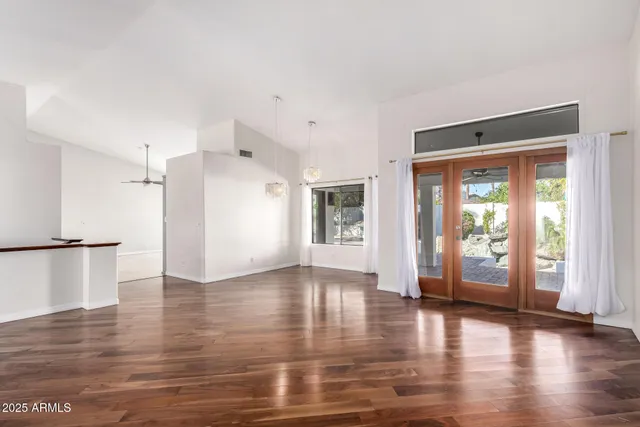 a view of an empty room with window and wooden floor