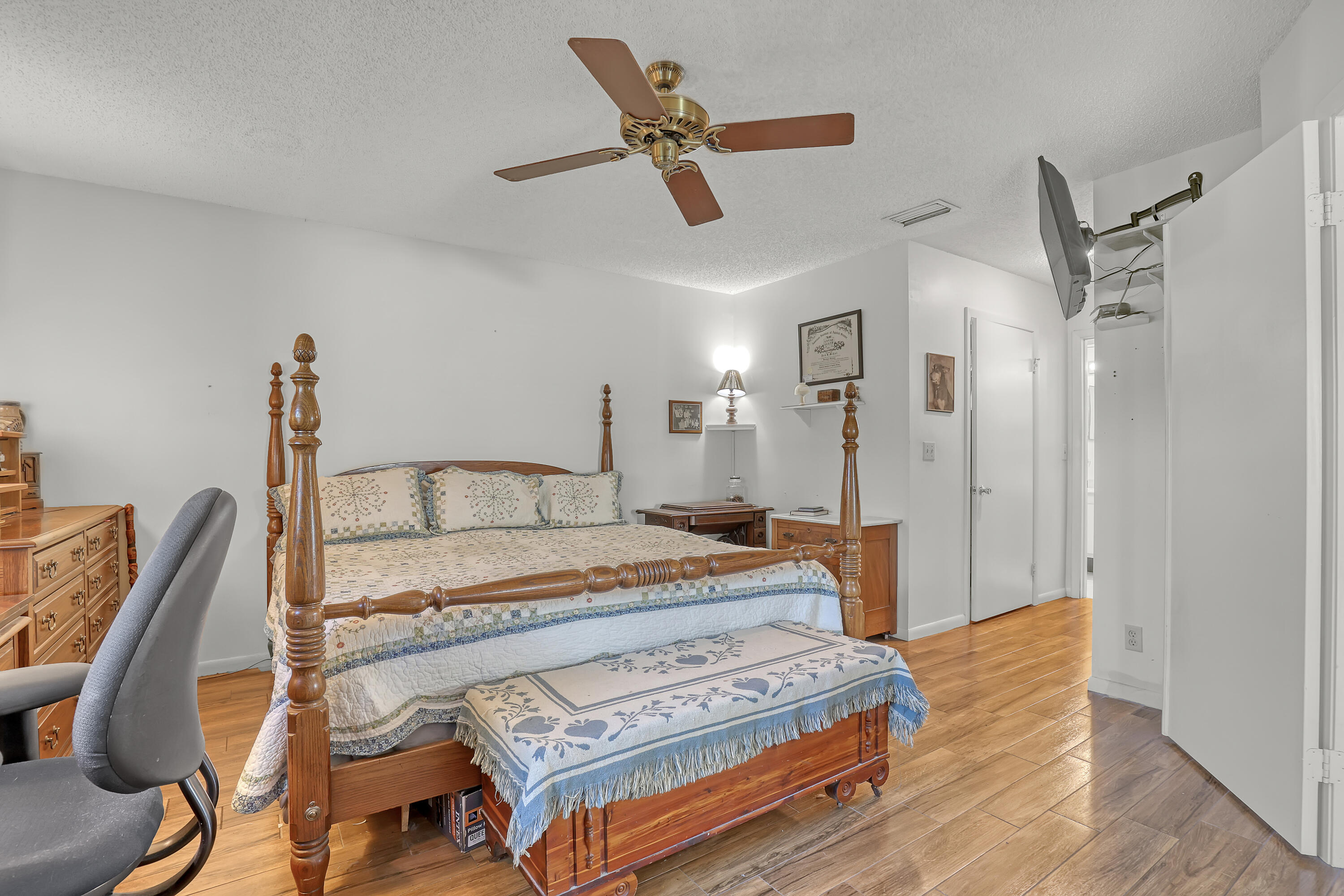 13116 Quiet Woods Road, Unit A Wellington, FL 33414 - Photo 18 of 31 a bedroom with a bed a chandelier and the dresser