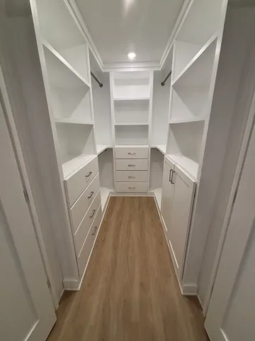a walk in closet with wooden floor