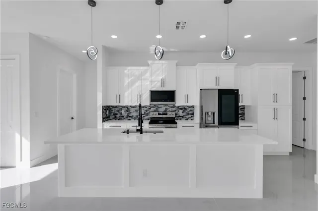 a large kitchen with kitchen island a large counter top space appliances and cabinets