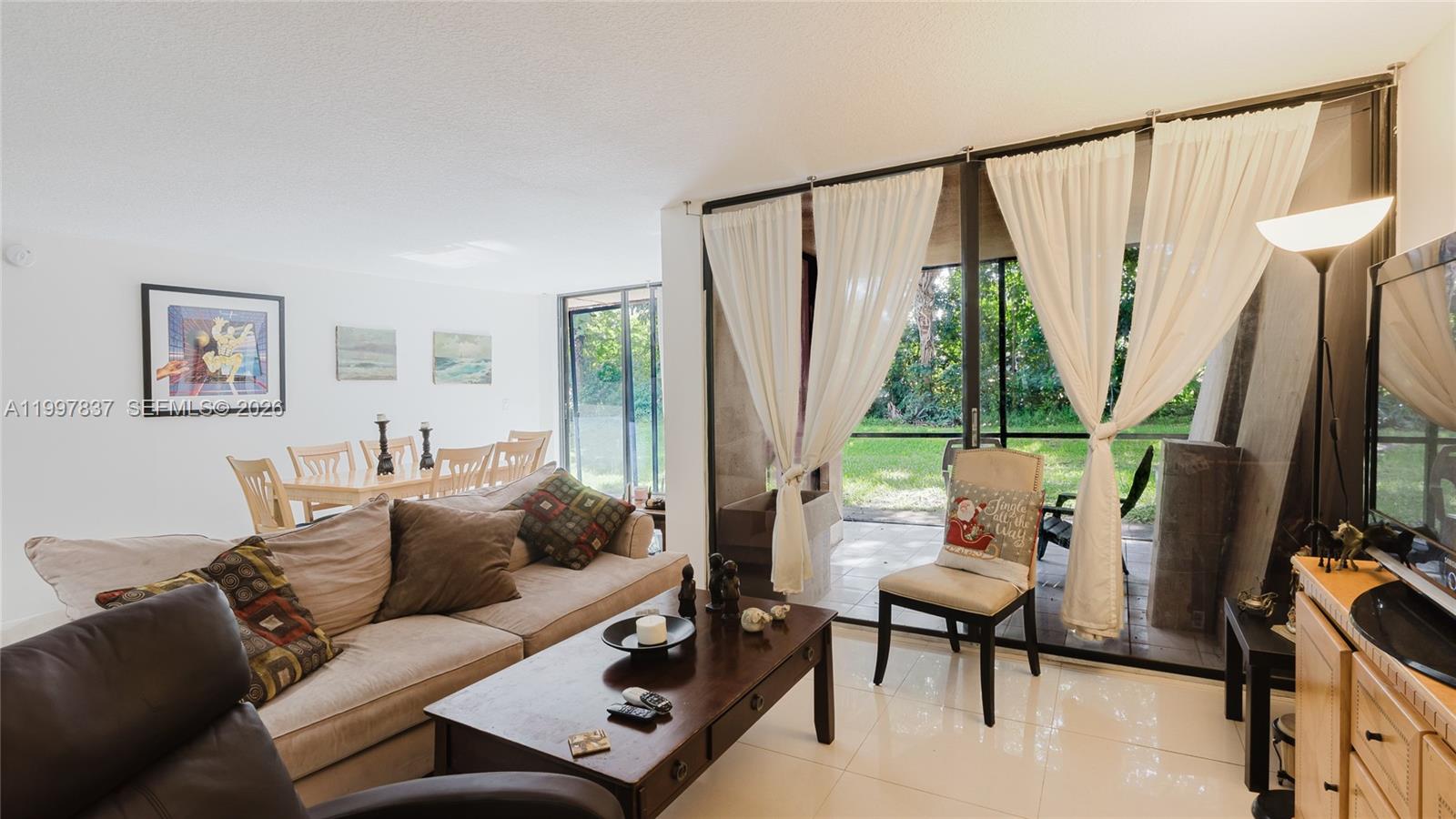 101 Southwest 96th Terrace, Unit 101 Plantation, FL 33324 - Photo 15 of 37 a living room with furniture a large window and a flat screen tv