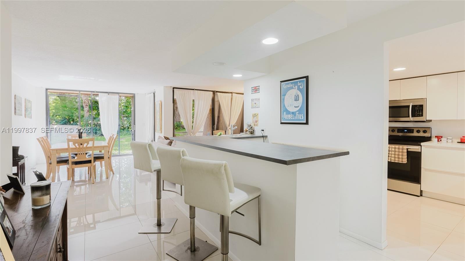 101 Southwest 96th Terrace, Unit 101 Plantation, FL 33324 - Photo 7 of 37 a kitchen with granite countertop a refrigerator a stove a dining table and chairs next to a window