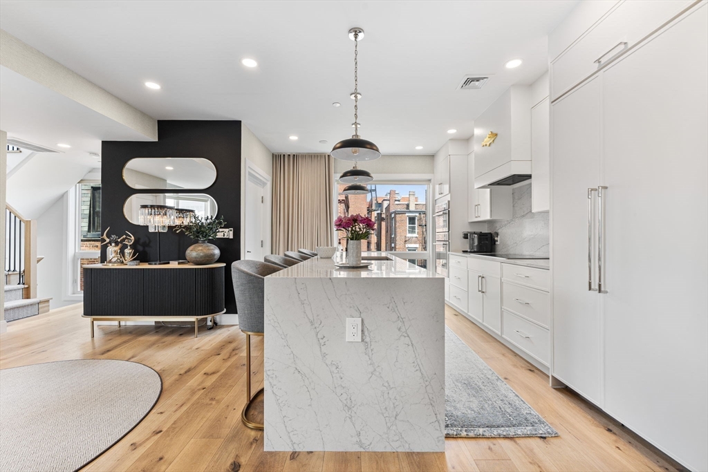 43 Stillman Street, Unit PH Boston, MA 02113 - Photo 7 of 17 a kitchen with stainless steel appliances granite countertop a stove a sink a refrigerator and a dining table with wooden floor