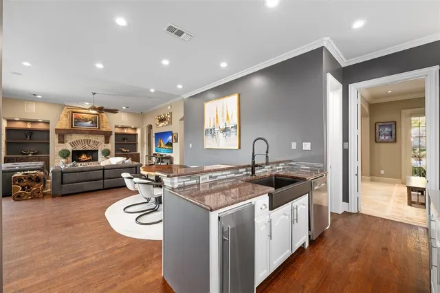 a kitchen that has a lot of cabinets a sink and wooden floor
