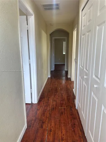a view of a hallway with wooden floor and a bathroom