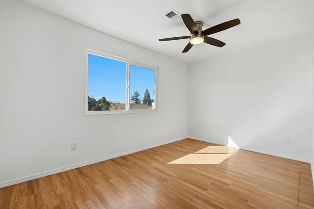a view of a big room with wooden floor and a ceiling fan