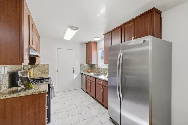 a kitchen with stainless steel appliances granite countertop a refrigerator and a stove