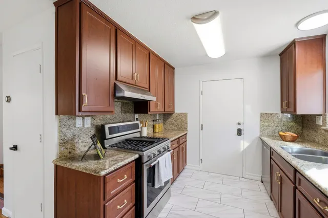 a kitchen with stainless steel appliances granite countertop a stove a sink and a refrigerator