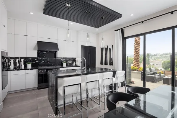 a kitchen with stainless steel appliances granite countertop a stove top oven a sink a dining table and chairs