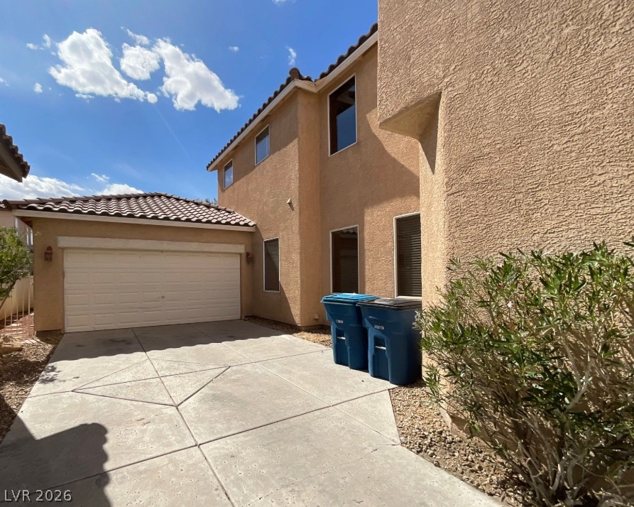 10841 Paradise Road Henderson, NV 89052 - Photo 2 of 35 A well-maintained concrete driveway leads to the attached garage of this two-story residence.