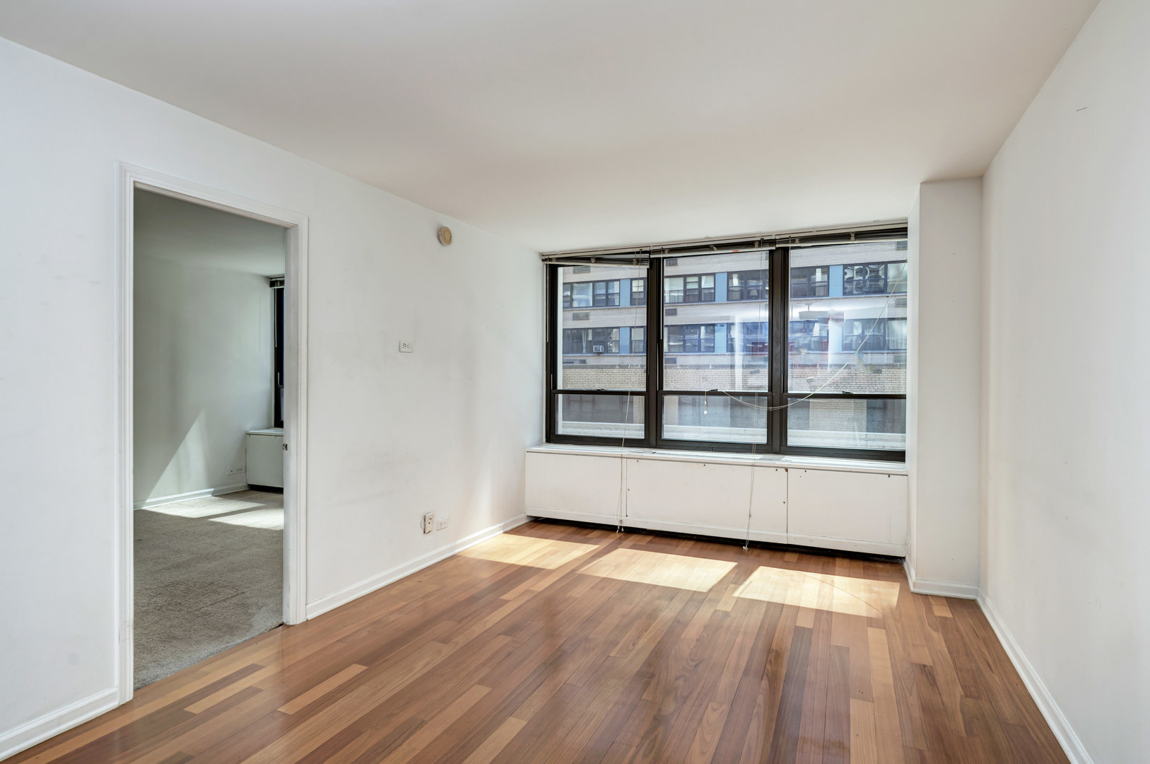 222 East Pearson Street, Unit 203 Chicago, IL 60611 - Photo 7 of 29 an empty room with wooden floor and windows