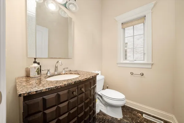a bathroom with a granite countertop toilet a sink and a mirror