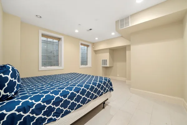 a bedroom with a large bed and two windows
