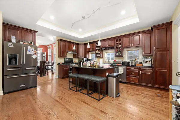 a kitchen with stainless steel appliances kitchen island granite countertop a refrigerator a stove top oven and a sink with cabinets