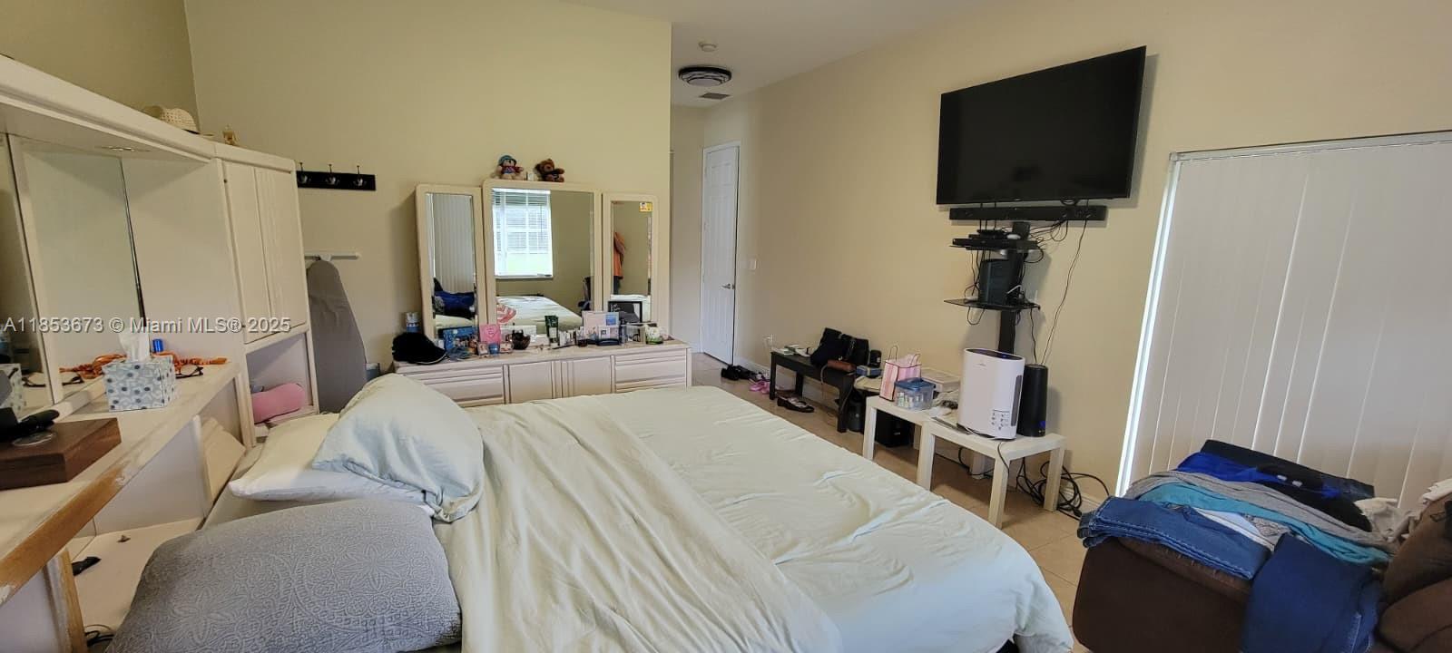 13281 Southwest 206th Terrace Miami, FL 33177 - Photo 14 of 18 a bedroom with a bed and a flat tv screen on wall